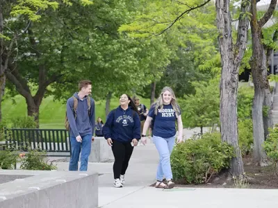 Three students wearing Oregon Tech shirts, walking across campus. 