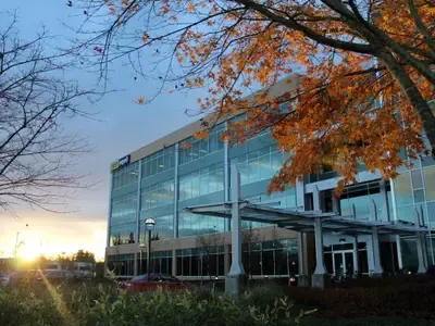 Picture of Oregon Tech's portlad metro campus building at sunset with fall leaves in the foreground